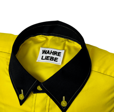 a yellow shirted pillow with a black collar and label