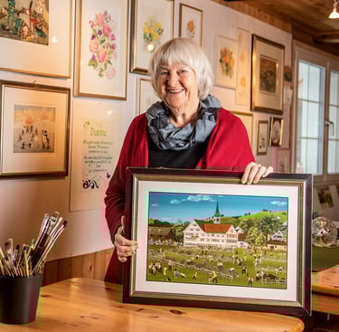 Eine Frau, die ein Bild eines Gemäldes eines Hauses hält