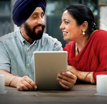 a man and woman sitting at a table with a iPad in their hands looking at each other