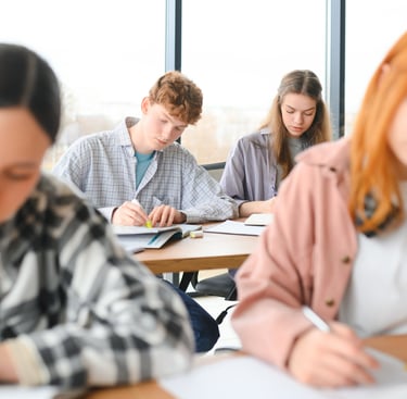 Diverse high school students studying and taking notes in a bright modern classroom.