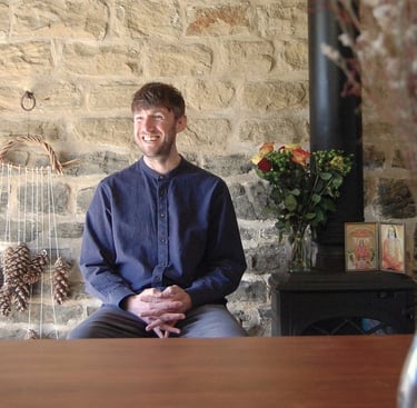 a meditation teacher sitting in front of a class with a vase of flowers