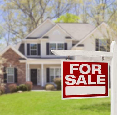 large house and yard with for sale sign in front