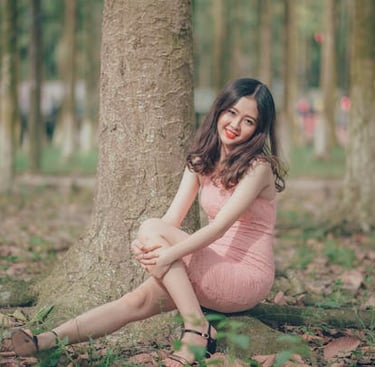 a woman sitting on a tree stump in a park