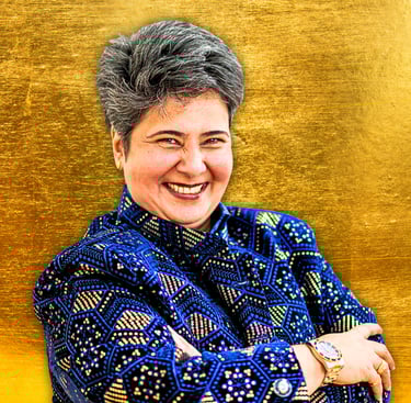 Indian woman with crossed arms smiling at camera, She is wearing a royal blue jacket with gold.