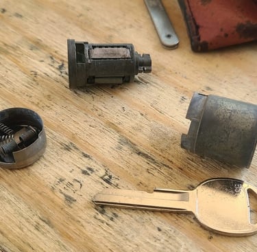 Ignition pieces taken apart beside a key representing ignition repair locksmith service in Weaverville, NC