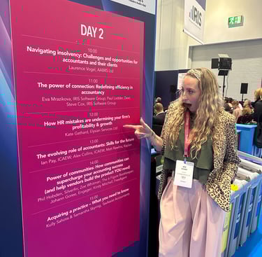 a woman standing in front of a sign that says Elysian Services HR Ltd speaker slot at Accountex