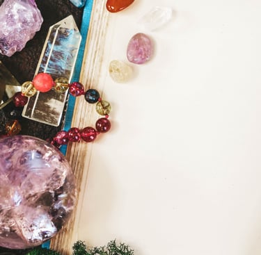 Healing crystals, amethyst sphere, and beaded bracelet arranged on an open blank vintage journal.