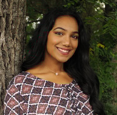 a headshot of a woman with long hair in front of a tree