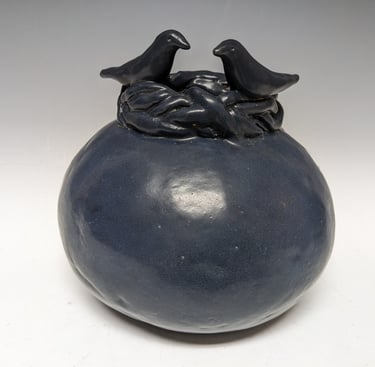 Round black clay pot with birds on top