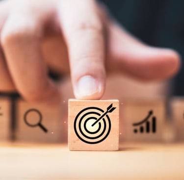 a person's finger pressing a button on a wooden block with a target arrow