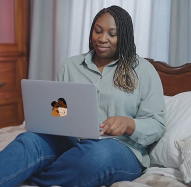 Black woman sitting on bed with laptop