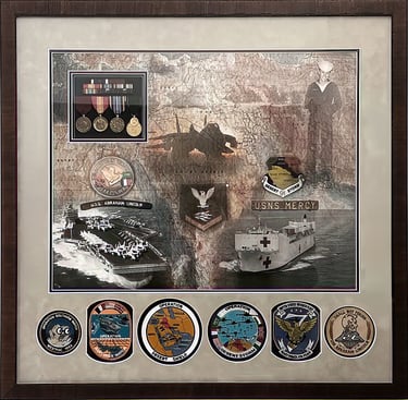 Military shadow box with US Navy medals, patches, and photos of USS Abraham Lincoln and USNS Mercy.