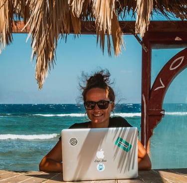 Digital nomad woman learning spanish on a laptop at a tropical beach office with ocean views.
