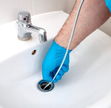 Using a drain snake to clean a clogged bathroom sink