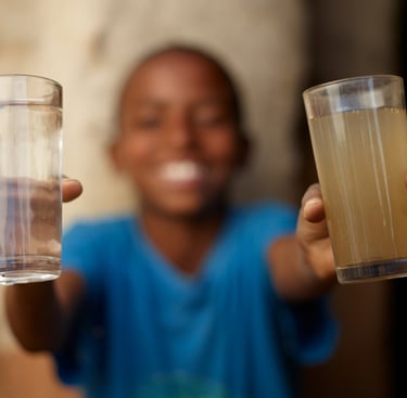charity: water picture of young boy holding a glass of clean water and a glass of dirty water.