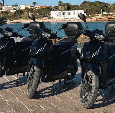 three motorcycles parked on a brick wall near a body of water
