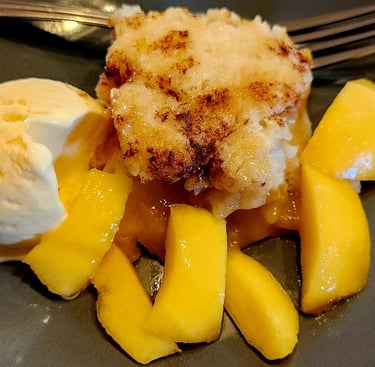 a peach cobbler dessert with a scoop of ice cream and a fork
