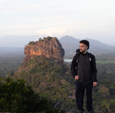 A man standing on a mountain, posing in front of Sigiriya Rock (Sri Lanka), in the background. Beautiful landscape with trees