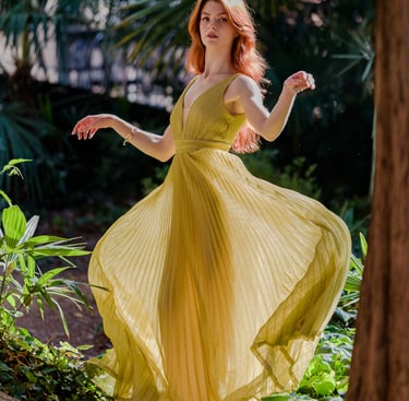 Ragazza in mezzo alla vegetazione con un abito dorato svolazzante