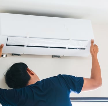 a man is fixing a air conditioner in a room