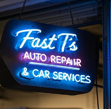 Neon sign in blue says Fast T's Auto Repair & Car Services with an auto repair garage in the background