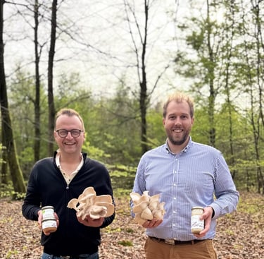 two men standing next to each other holding beer