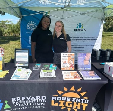 two women smiling in front of a table offering free information about move into light initiative