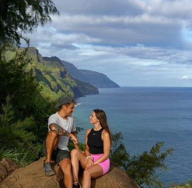 a man and woman sitting on a rock in hawaii