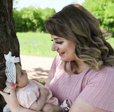 a woman smiling down at her baby held in her arms