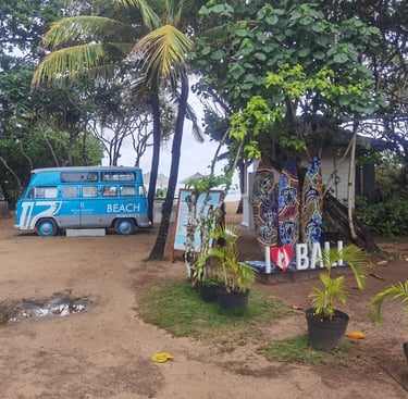 A vintage blue food truck parked near tropical palm trees and surfboards at a Bali beach resort.