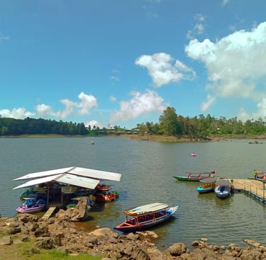 Dermaga perahu wisata di tepi Situ Cileunca dengan perahu-perahu berwarna-warni yang bersandar di bawah langit biru cerah