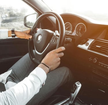 Un hombre sostiene el volante de un coche. Lleva un reloj en la muñeca izquierda