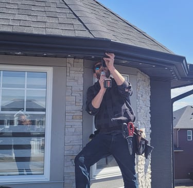 father installing permanent holiday lights on a house in Calgary