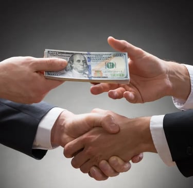 Two hands shake while one hand passes a stack investment money to the other.