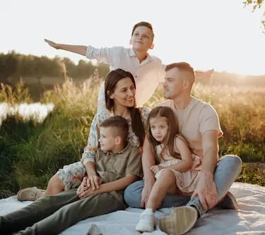 large young Caucasian family smiling at a sunset picnic