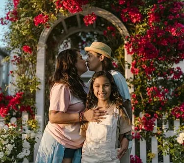 young latin family with girl child in a rose garden at sunset