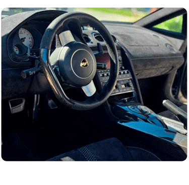 Luxury interior of a Lamborghini featuring a carbon fiber steering wheel and Alcantara dashboard.