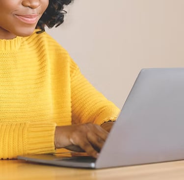 Black female wearing a yellow cardigan, working on the computer