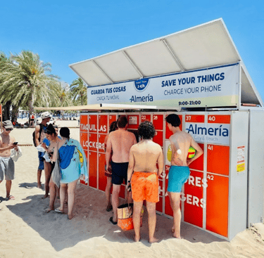 Piros színű strandszekrény előtt sorban állnak a strandolók