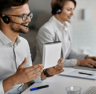 Smiling male customer service representative wearing a headset while working in a modern office.