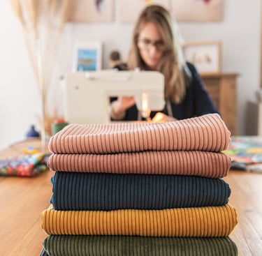 séance photo professionnelle d'une couturière en train de coudre avec ses tissus devant