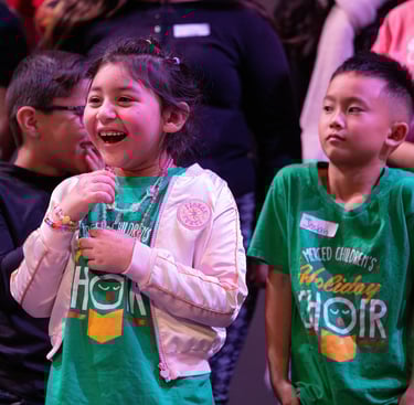 A happy young girl laughing during a performance with the Merced Children's Holiday Choir.