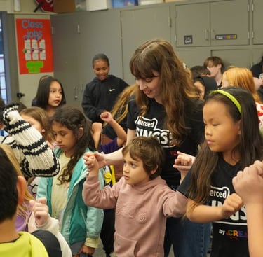 Elementary students and teacher participating in a classroom dance activity for physical education.