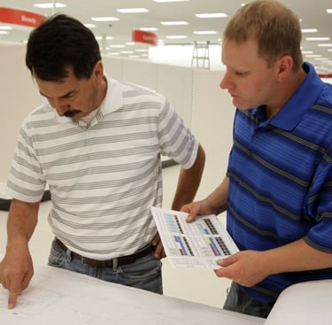 Two technicians in a retail setting reviewing printed documents together.
