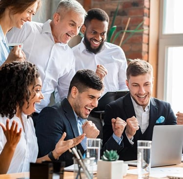 a group of people sitting around a table with a laptop