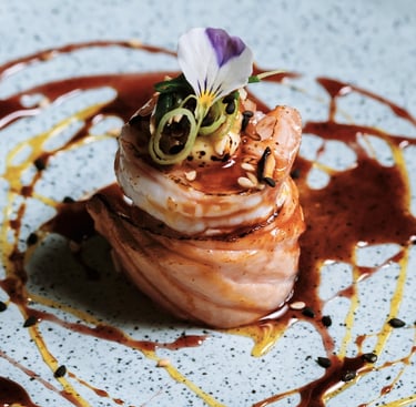 Fileira de sushis enrolados com salmão e cobertura cremosa, servidos em uma travessa longa sobre mesa de madeira.