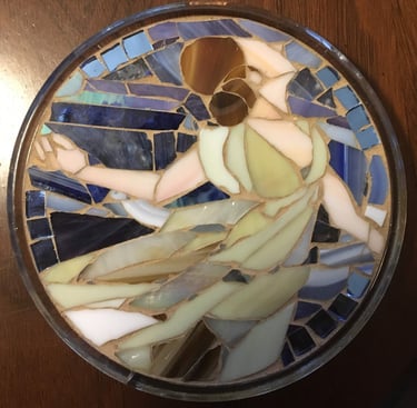 Circular stained glass mosaic titled "Isadora" by Julie Curson, depicting a graceful figure.
