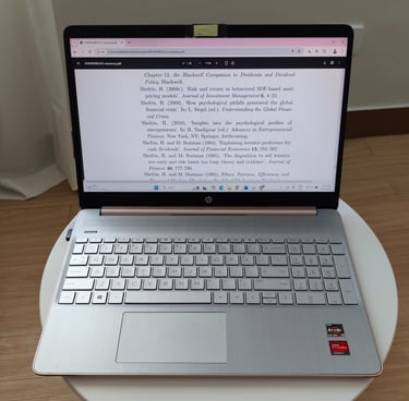 Silver HP laptop on a white table displaying a PDF, with a chiclet keyboard and wooden background.