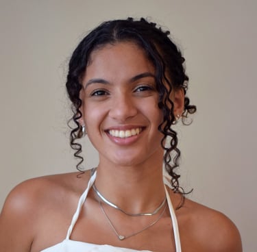 Uma mulher com blusa branca e cabelos cacheados presos no alto da cabeça