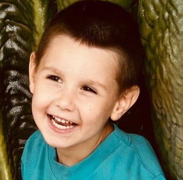 A giggling 6-year-old boy with brown eyes.